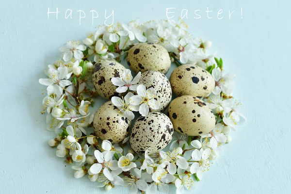 Easter background with Easter eggs in nest of spring flowers. Top view with copy space. Happy Easter Spring Festive greeting card. Holidays arrangement. Text in English Happy Easter