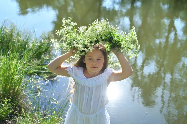 Girl in beautiful wreath on summer meadow near the river . Feast of Ivan Kupala.Midsummer.7th July, traditional slavic holiday with fortune-telling and divination rituals in Ukraine.Selective focus