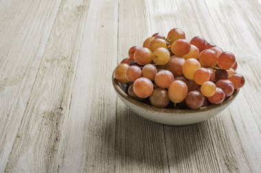 Tahta masadaki bir kasedeki üzümler