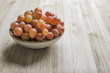 Tahta masadaki bir kasedeki üzümler