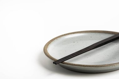 A Pair Of Chopsticks With Stoneware Plate clipart