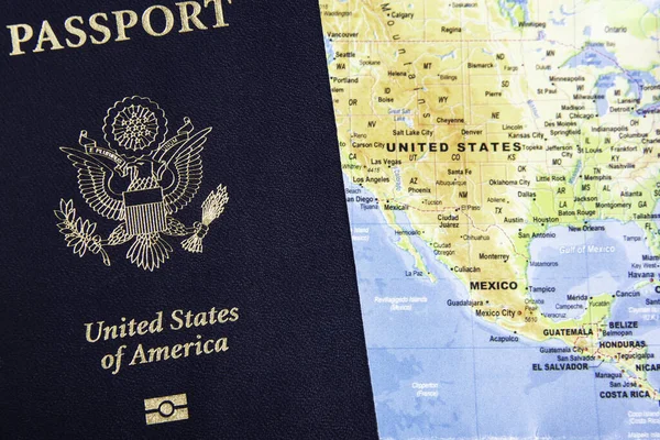 The foil-stamped dark blue front cover of an American passport set on a world map background.