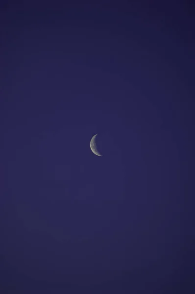 一缕纤细的银色月亮落在广袤无云的蓝天上 — 图库照片
