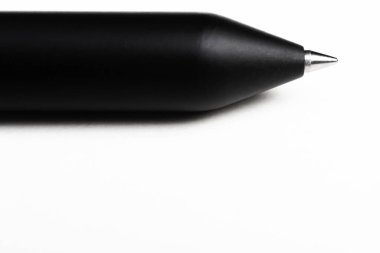 A macro shot of the writing tip with a portion of the barrel of a streamlined modern black ballpoint pen set on white background. clipart
