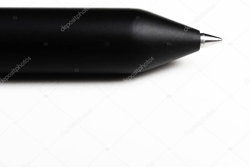 A macro shot of the writing tip with a portion of the barrel of a streamlined modern black ballpoint pen set on white background.