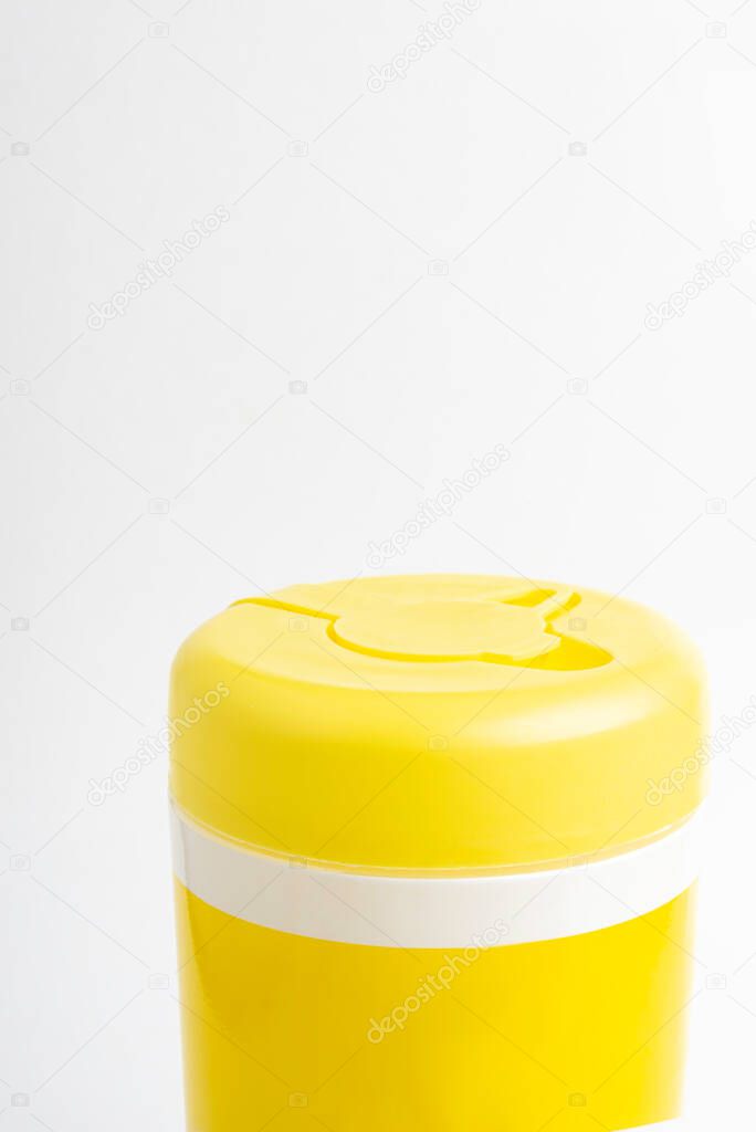 A macro shot of a closed yellow push top cap of a disinfectant wet wipes product container set on plain white background.