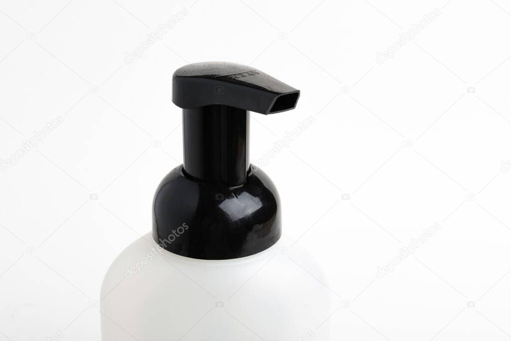 A close-up of the top portion of a black-and-white foaming hand soap dispenser set on a plain white background,