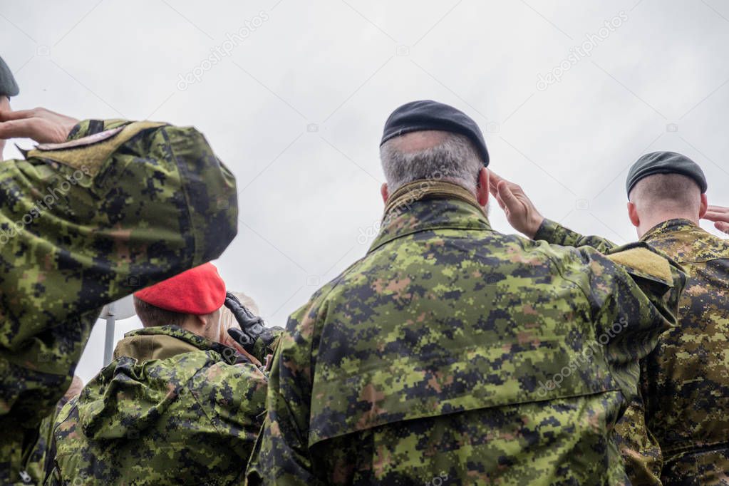 Canadian Army soldiers stand and watch the parade. Military in camouflage. Warrior clothes. Autumn. It's a nasty day.