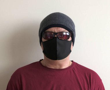 Coronavirus 'tan korunan bir adamın portresi. Beyaz, lateks eldivenler. Enfeksiyonlara, virüslere, mikroplara karşı el koruması. Deride izolasyon. Yüzünde kumaş bir maske var. Gözlerde gözlük.. 