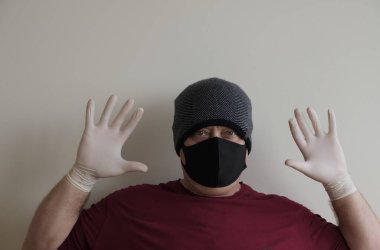 Coronavirus 'tan korunan bir adamın portresi. Beyaz, lateks eldivenler. Enfeksiyonlara, virüslere, mikroplara karşı el koruması. Deride izolasyon. Yüzünde kumaş bir maske var. Gözlerde gözlük.. 