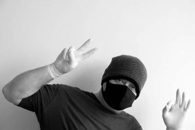 Coronavirus 'tan korunan bir adamın portresi. Beyaz, lateks eldivenler. Enfeksiyonlara, virüslere, mikroplara karşı el koruması. Deride izolasyon. Yüzünde kumaş bir maske var. Gözlerde gözlük.. 