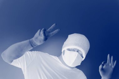 Coronavirus 'tan korunan bir adamın portresi. Beyaz, lateks eldivenler. Enfeksiyonlara, virüslere, mikroplara karşı el koruması. Deride izolasyon. Yüzünde kumaş bir maske var. Gözlerde gözlük.. 