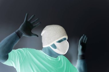 Coronavirus 'tan korunan bir adamın portresi. Beyaz, lateks eldivenler. Enfeksiyonlara, virüslere, mikroplara karşı el koruması. Deride izolasyon. Yüzünde kumaş bir maske var. Gözlerde gözlük.. 