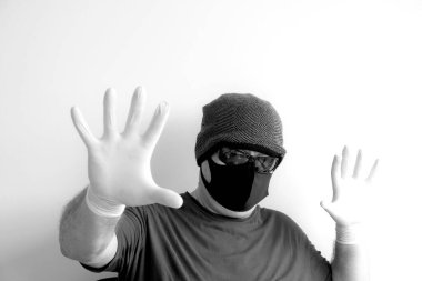 Coronavirus 'tan korunan bir adamın portresi. Beyaz, lateks eldivenler. Enfeksiyonlara, virüslere, mikroplara karşı el koruması. Deride izolasyon. Yüzünde kumaş bir maske var. Gözlerde gözlük.. 