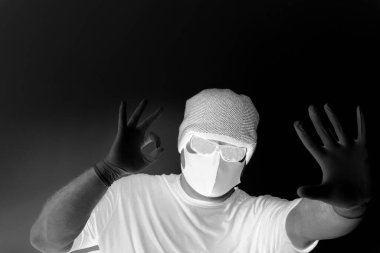 Coronavirus 'tan korunan bir adamın portresi. Beyaz, lateks eldivenler. Enfeksiyonlara, virüslere, mikroplara karşı el koruması. Deride izolasyon. Yüzünde kumaş bir maske var. Gözlerde gözlük.. 