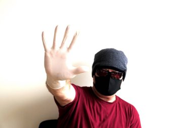 Coronavirus 'tan korunan bir adamın portresi. Beyaz, lateks eldivenler. Enfeksiyonlara, virüslere, mikroplara karşı el koruması. Deride izolasyon. Yüzünde kumaş bir maske var. Gözlerde gözlük.. 