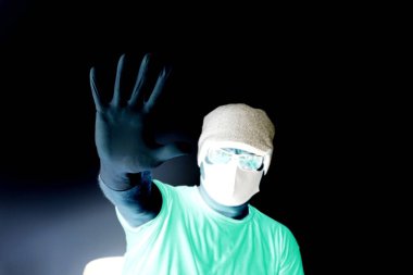 Coronavirus 'tan korunan bir adamın portresi. Beyaz, lateks eldivenler. Enfeksiyonlara, virüslere, mikroplara karşı el koruması. Deride izolasyon. Yüzünde kumaş bir maske var. Gözlerde gözlük.. 