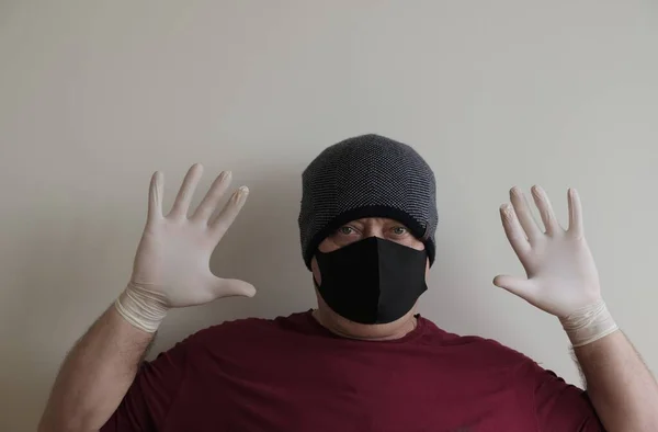 Portrait of a man protected from coronavirus. White, latex gloves. Hand protection against infections, viruses, germs. Isolation of the skin. On the face is a fabric mask. Glasses on the eyes.