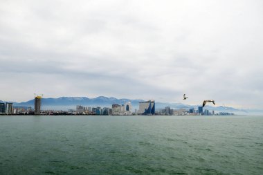 Kafkasya 'nın eteklerinin manzarası. Batumi ilçesi. Yüksek tepelerde kar yatıyor. Alt dağlarda yerleşim yerleri var. Arazinin rengi farklı..