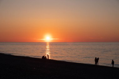 Karadeniz 'de gün batımı. İnsanlar sahilde ve rıhtımda yürüyor. Sessiz, sakin bir akşam.