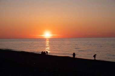 Karadeniz 'de gün batımı. İnsanlar sahilde ve rıhtımda yürüyor. Sessiz, sakin bir akşam.