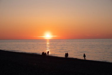 Karadeniz 'de gün batımı. İnsanlar sahilde ve rıhtımda yürüyor. Sessiz, sakin bir akşam.