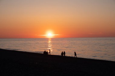Karadeniz 'de gün batımı. İnsanlar sahilde ve rıhtımda yürüyor. Sessiz, sakin bir akşam.