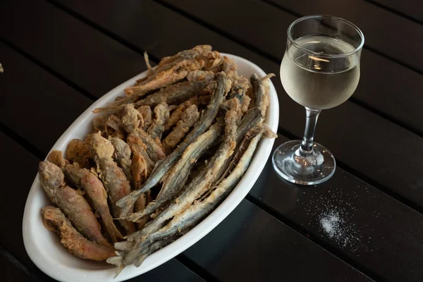 Balık iğnesi, kızartılmış kırmızı kefal. Beyaz tabakta altın renkli balık. Bir bardak beyaz şarap. Deniz ürünleri restoranı. Günaydın Georgia..