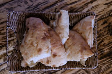 Masadaki sepetteki pita ekmeği parçaları. Lavaş, buğday unundan yapılmış ince bir tortilla şeklinde mayalanmamış beyaz ekmektir ve çoğunlukla Kafkaslar, İran, Afganistan ve Küçük Asya 'nın diğer bölgeleri arasında dağıtılır..