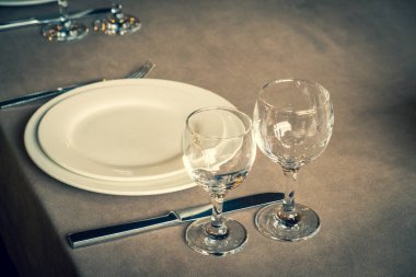 Restorandaki servis masası. Bir kafedeki masa örtüsünün üzerindeki temiz tabaklar ve aletler. Parlak şeffaf bardaklar. Beyaz tabaklar. Konukların resepsiyonu için hazırlandı. Yüksek servis.