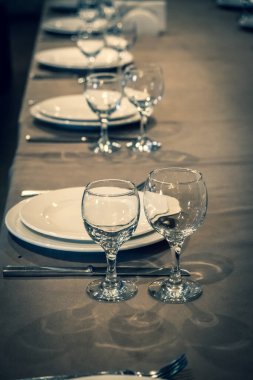 Restorandaki servis masası. Bir kafedeki masa örtüsünün üzerindeki temiz tabaklar ve aletler. Parlak şeffaf bardaklar. Beyaz tabaklar. Konukların resepsiyonu için hazırlandı. Yüksek servis.