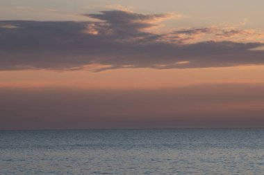 Gün batımında deniz manzarası. Küçük bulutlar. Sessiz rüzgar, sıcak..