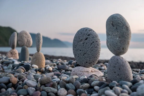 Summer is coming soon in a pandemic. Deserted city beach on the Black Sea. Sculptures of stones, a symbol of people. Stone people. Imitation of lovers. Art installation from pebbles. Meditation at sea.