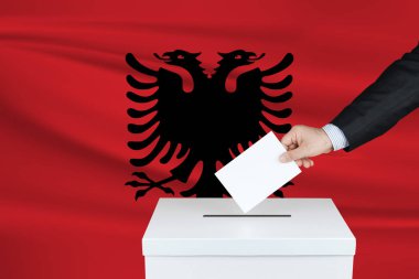 Arnavutluk 'ta seçim. Oylarını sandığa koyan adamın eli. Arka planda Arnavutluk bayrağı salladı.