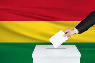 Bolivya 'da seçim. Oylarını sandığa koyan adamın eli. Arkaplanda Bolivya bayrağı sallandı.