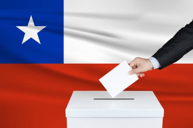 Şili 'de seçim. Oylarını sandığa koyan adamın eli. Arka planda Dalgalı Şili bayrağı.