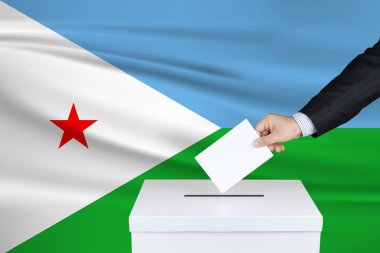 Cibuti 'de seçim. Oylarını sandığa koyan adamın eli. Arka planda Cibuti bayrağı sallandı.