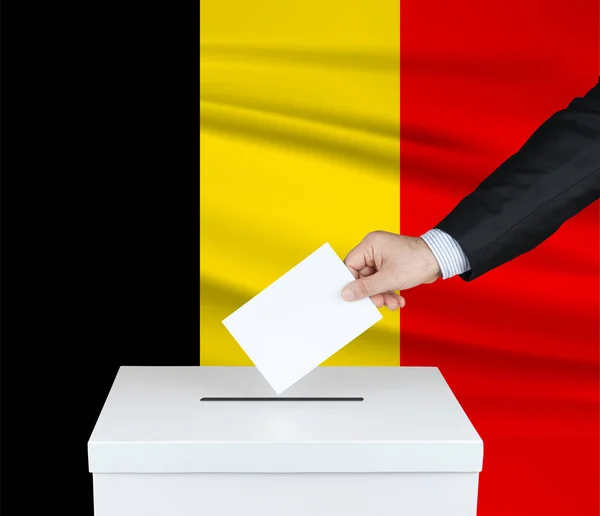 比利时的选举 把他的选票放进投票箱的人的手 背风飘扬的比利时国旗 — 图库照片