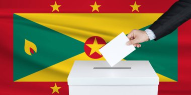 Grenada 'da seçim. Oylarını sandığa koyan adamın eli. Arka planda el sallanmış Grenada bayrağı.                               