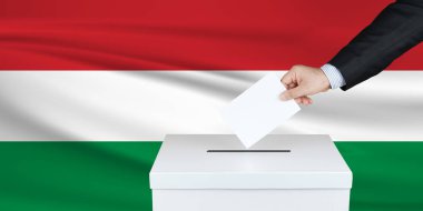 Macaristan 'da seçim. Oylarını sandığa koyan adamın eli. Arka planda Macaristan bayrağı salladı.                               