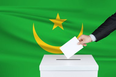 Moritanya 'da seçim. Oylarını sandığa koyan adamın eli. Arka planda Moritanya bayrağı salladı.                               