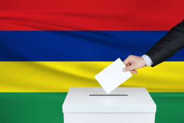 Mauritius 'ta seçim. Oylarını sandığa koyan adamın eli. Arka planda Mauritius bayrağı salladı.                               