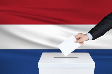 Hollanda 'da seçim. Oylarını sandığa koyan adamın eli. Arka planda Dalgalı Hollanda bayrağı.                               