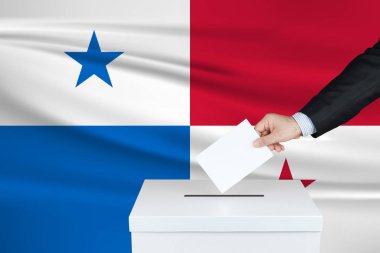 Panama 'da seçim. Oylarını sandığa koyan adamın eli. Arka planda Panama bayrağı sallandı.                               