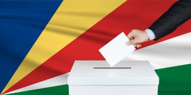 Seyşeller 'de seçim. Oylarını sandığa koyan adamın eli. Arka planda Seyşeller bayrağı sallandı.                               