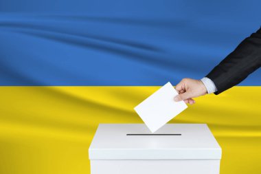 Ukrayna 'da seçim. Oylarını sandığa koyan adamın eli. Arka planda dalgalı Ukrayna bayrağı.                               
