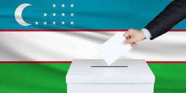 Özbekistan 'da seçim. Oylarını sandığa koyan adamın eli. Arka planda Özbekistan bayrağı sallandı.                               