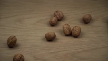 Cevizler Düşer ve Ekranı Doldur. Cevizler ahşap arka planda yuvarlanıyor. Yavaş çekim.
