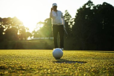 Bulanık golfçü akşam golf sahasında güneş altında golf oynuyor.