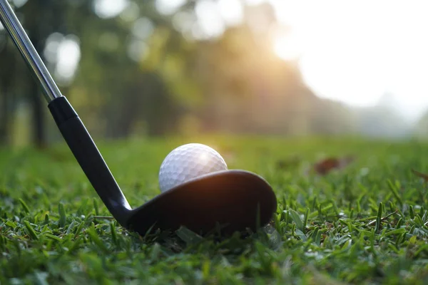 Clube de golfe desfocado e bola de golfe perto no campo de grama com sol — Fotografia de Stock